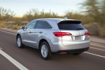 Picture of a driving 2015 Acura RDX in Silver Moon from a rear three-quarter perspective
