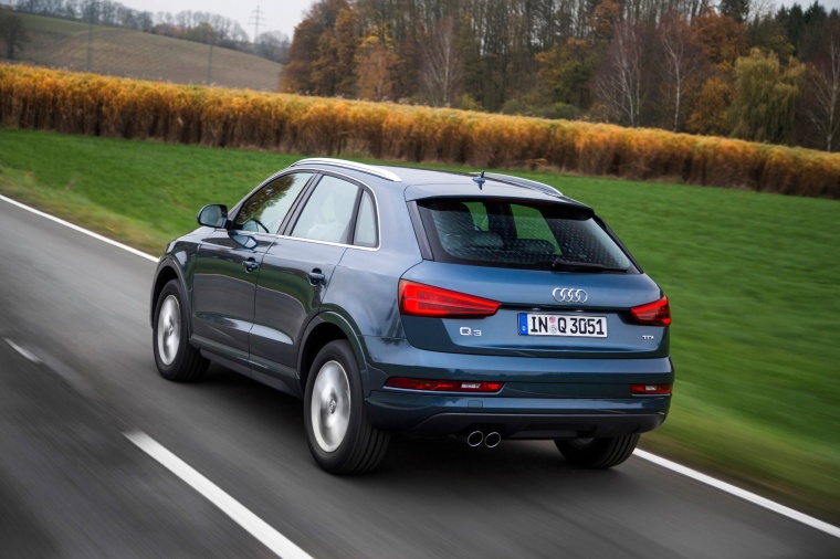 Picture of a driving 2015 Audi Q3 in Cobalt Blue Metallic from a rear left perspective