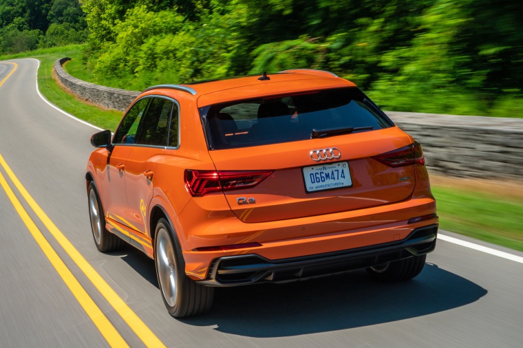 Picture of a driving 2020 Audi Q3 45 quattro in Pulse Orange from a rear left perspective