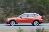 Picture of a driving 2014 BMW X1 in Valencia Orange Metallic from a left side perspective