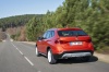 Picture of a driving 2014 BMW X1 in Valencia Orange Metallic from a rear left perspective
