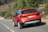 Picture of a driving 2014 BMW X1 in Valencia Orange Metallic from a rear perspective