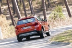 Picture of a driving 2014 BMW X1 in Valencia Orange Metallic from a rear right perspective
