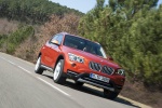 Picture of a driving 2014 BMW X1 in Valencia Orange Metallic from a front right three-quarter perspective