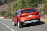Picture of a driving 2015 BMW X1 in Valencia Orange Metallic from a rear perspective