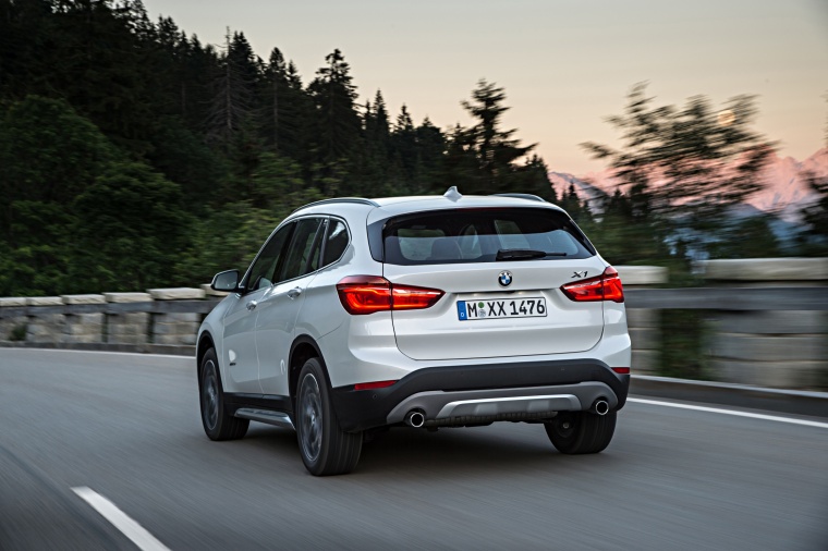 Picture of a driving 2016 BMW X1 xDrive28i in Alpine White from a rear left perspective