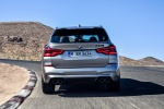 Picture of a driving 2020 BMW X3 M Competition in Donington Gray Metallic from a rear perspective