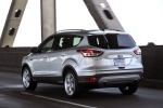 Picture of a driving 2014 Ford Escape Titanium 4WD in Ingot Silver Metallic from a rear left three-quarter perspective