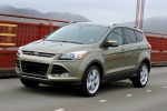 Picture of a driving 2014 Ford Escape Titanium 4WD in Ginger Ale Metallic from a front left three-quarter perspective