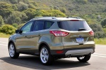 Picture of a driving 2015 Ford Escape Titanium 4WD from a rear left three-quarter perspective