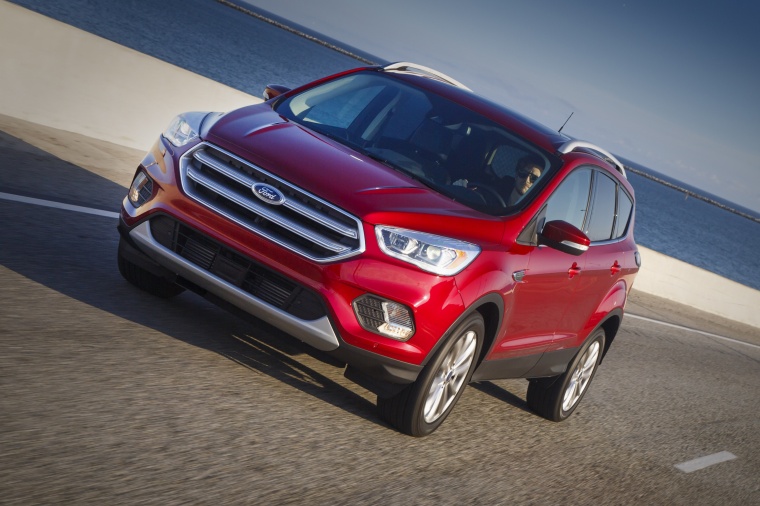 Picture of a driving 2017 Ford Escape Titanium in Ruby Red Metallic Tinted Clearcoat from a front left perspective