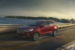 Picture of a driving 2017 Ford Escape Titanium in Ruby Red Metallic Tinted Clearcoat from a front left three-quarter perspective