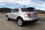 Picture of a driving 2014 Ford Explorer Limited 4WD in Ingot Silver Metallic from a rear left three-quarter perspective