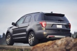 Picture of a driving 2016 Ford Explorer Platinum 4WD in Magnetic Metallic from a rear left three-quarter perspective