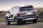 Picture of a driving 2016 Ford Explorer Platinum 4WD in Magnetic Metallic from a rear left perspective