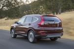 Picture of a driving 2015 Honda CR-V Touring AWD in Basque Red Pearl II from a rear left three-quarter perspective