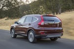 Picture of a driving 2016 Honda CR-V Touring AWD in Basque Red Pearl II from a rear left three-quarter perspective
