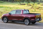 Picture of a driving 2017 Honda Ridgeline AWD in Deep Scarlet Pearl from a rear left three-quarter perspective