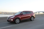 Picture of a driving 2014 Hyundai Santa Fe in Regal Red Pearl from a front left three-quarter perspective