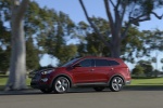 Picture of a driving 2014 Hyundai Santa Fe in Regal Red Pearl from a left side perspective