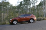 Picture of a driving 2014 Hyundai Santa Fe Sport in Serrano Red from a left side perspective
