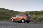 Picture of a driving 2014 Hyundai Santa Fe Sport in Serrano Red from a rear left three-quarter perspective