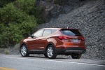 Picture of a driving 2014 Hyundai Santa Fe Sport in Serrano Red from a rear left perspective