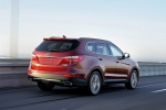 Picture of a driving 2014 Hyundai Santa Fe in Regal Red Pearl from a rear right perspective