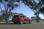 Picture of a driving 2015 Hyundai Santa Fe in Regal Red Pearl from a rear right three-quarter perspective