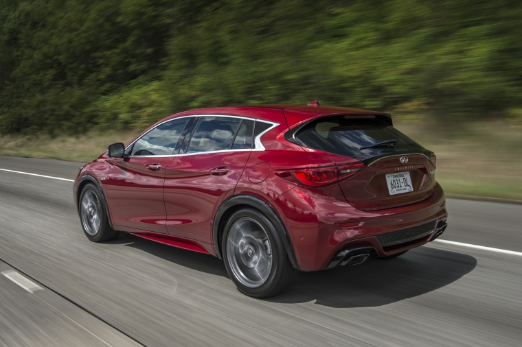Picture of a driving 2018 Infiniti QX30S in Magnetic Red from a rear left three-quarter perspective