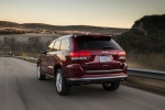 Picture of a driving 2014 Jeep Grand Cherokee Summit 4WD in Deep Cherry Red Crystal Pearlcoat from a rear left perspective