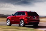 Picture of a driving 2014 Jeep Grand Cherokee SRT 4WD in Redline 2 Coat Pearl from a rear left perspective