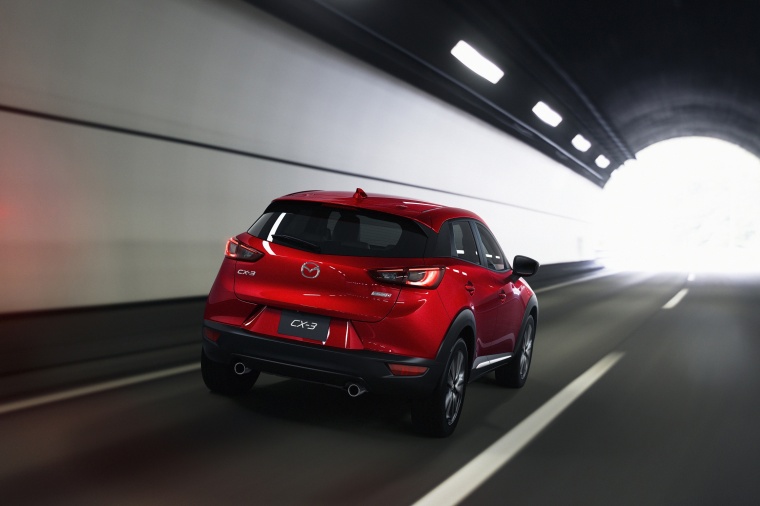 Picture of a driving 2016 Mazda CX-3 in Soul Red Metallic from a rear right perspective