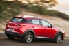 Picture of a driving 2016 Mazda CX-3 in Soul Red Metallic from a rear right three-quarter perspective