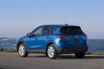 Picture of a driving 2014 Mazda CX-5 in Sky Blue Mica from a rear left three-quarter perspective