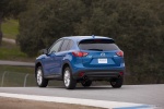 Picture of a driving 2014 Mazda CX-5 in Sky Blue Mica from a rear left perspective