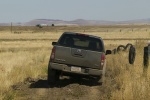 Picture of a driving 2014 Nissan Frontier Crew Cab PRO-4X 4WD in Night Armor from a rear perspective