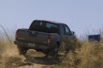 Picture of a driving 2014 Nissan Frontier Crew Cab PRO-4X 4WD in Night Armor from a rear right perspective