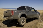 Picture of a driving 2014 Nissan Frontier Crew Cab PRO-4X 4WD in Night Armor from a rear right three-quarter perspective