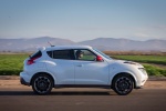 Picture of a driving 2016 Nissan Juke NISMO in White Pearl from a side perspective