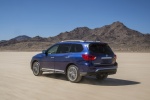 Picture of a driving 2018 Nissan Pathfinder Platinum 4WD in Caspian Blue from a rear left three-quarter perspective