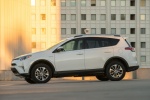 Picture of a driving 2016 Toyota RAV4 Hybrid XLE AWD in Super White from a side perspective