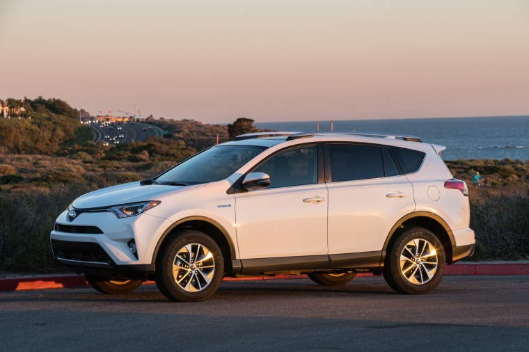 Picture of a driving 2017 Toyota RAV4 Hybrid XLE AWD in Super White from a front left three-quarter perspective