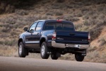 Picture of a driving 2014 Toyota Tacoma Double Cab SR5 V6 4WD in Blue Ribbon Metallic from a rear left perspective