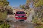 Picture of a driving 2014 Toyota Tacoma Access Cab V6 4WD in Barcelona Red Metallic from a frontal perspective